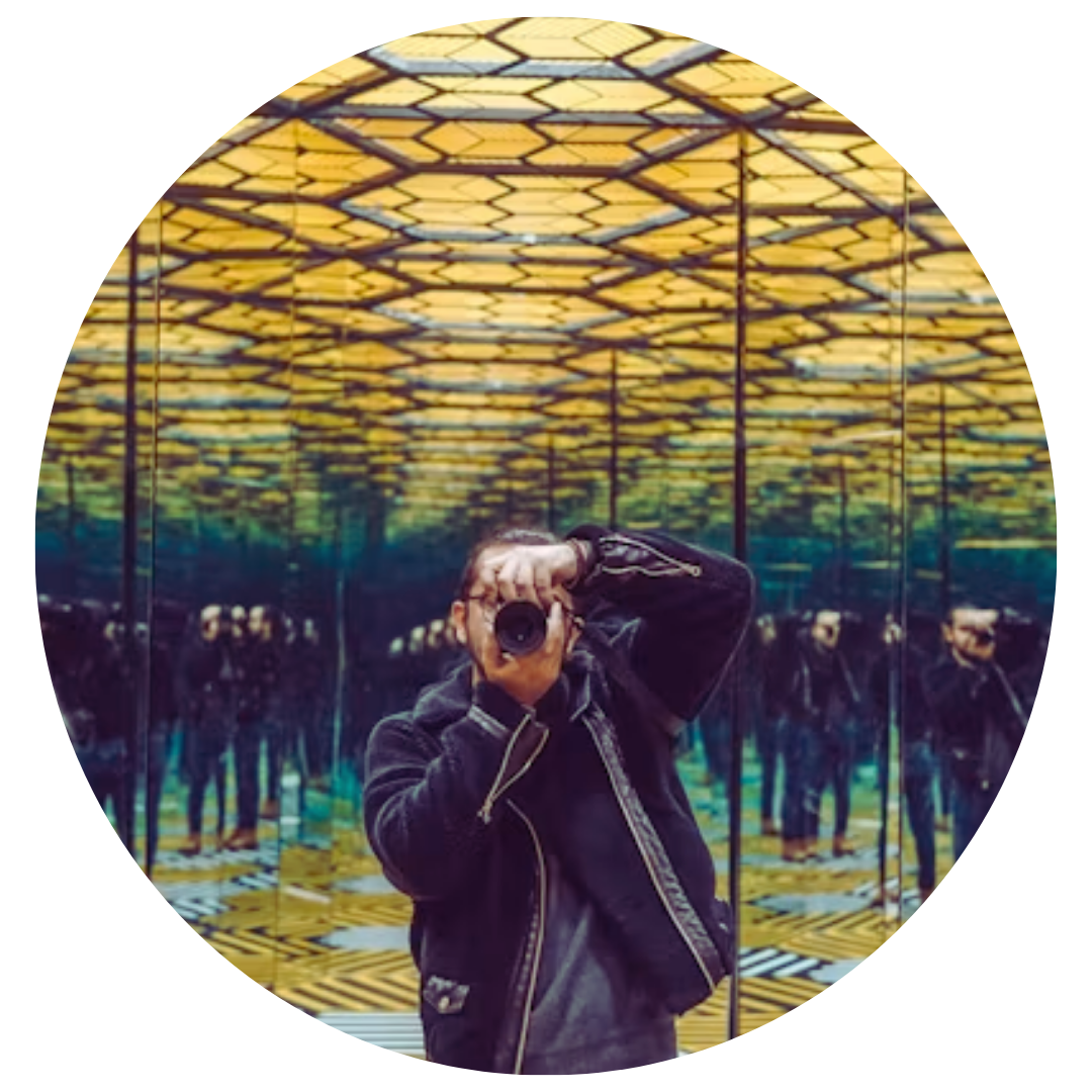 A man photographing himself inside a mirrored room, his reflection repeating with slight variations across the panels